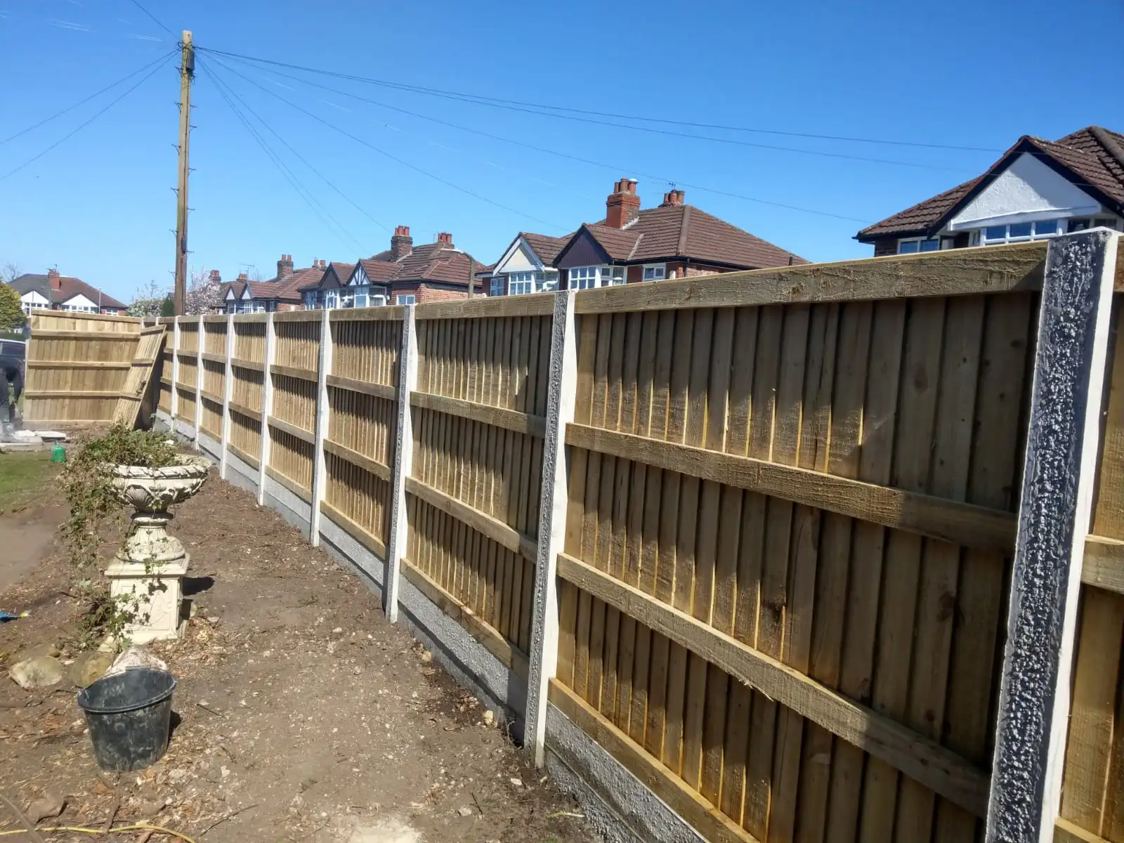 New panel fencing installation on concrete base in sunny conditions