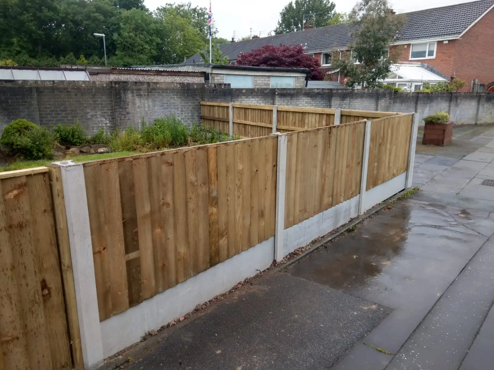 Commercial horizontal lap fencing installation with concrete posts in parking area