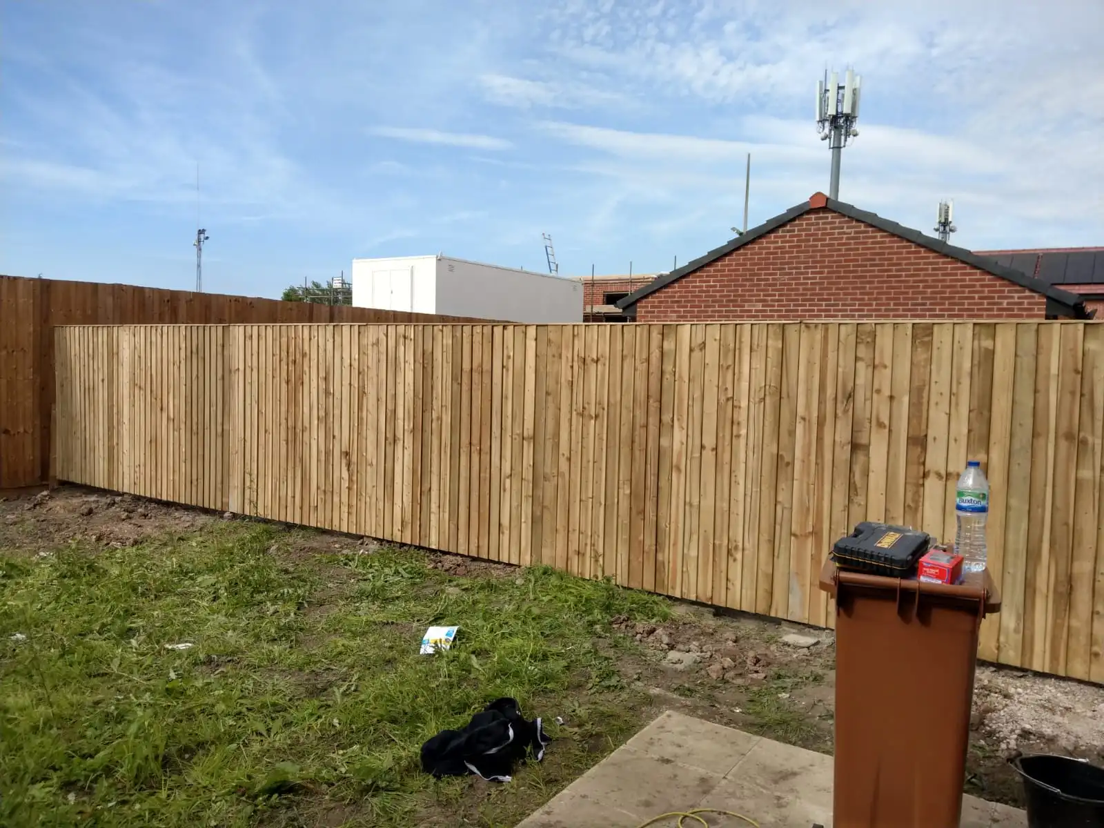 New vertical close-board fencing installation in residential garden with fresh turf
