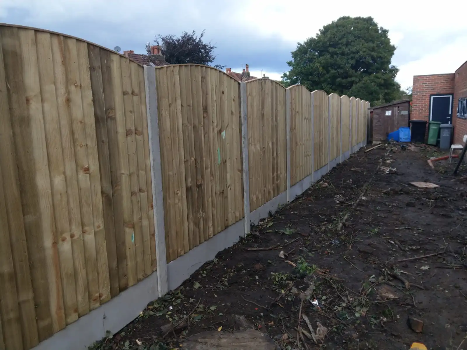 Curved wavy top close-board fencing with concrete posts and gravel boards
